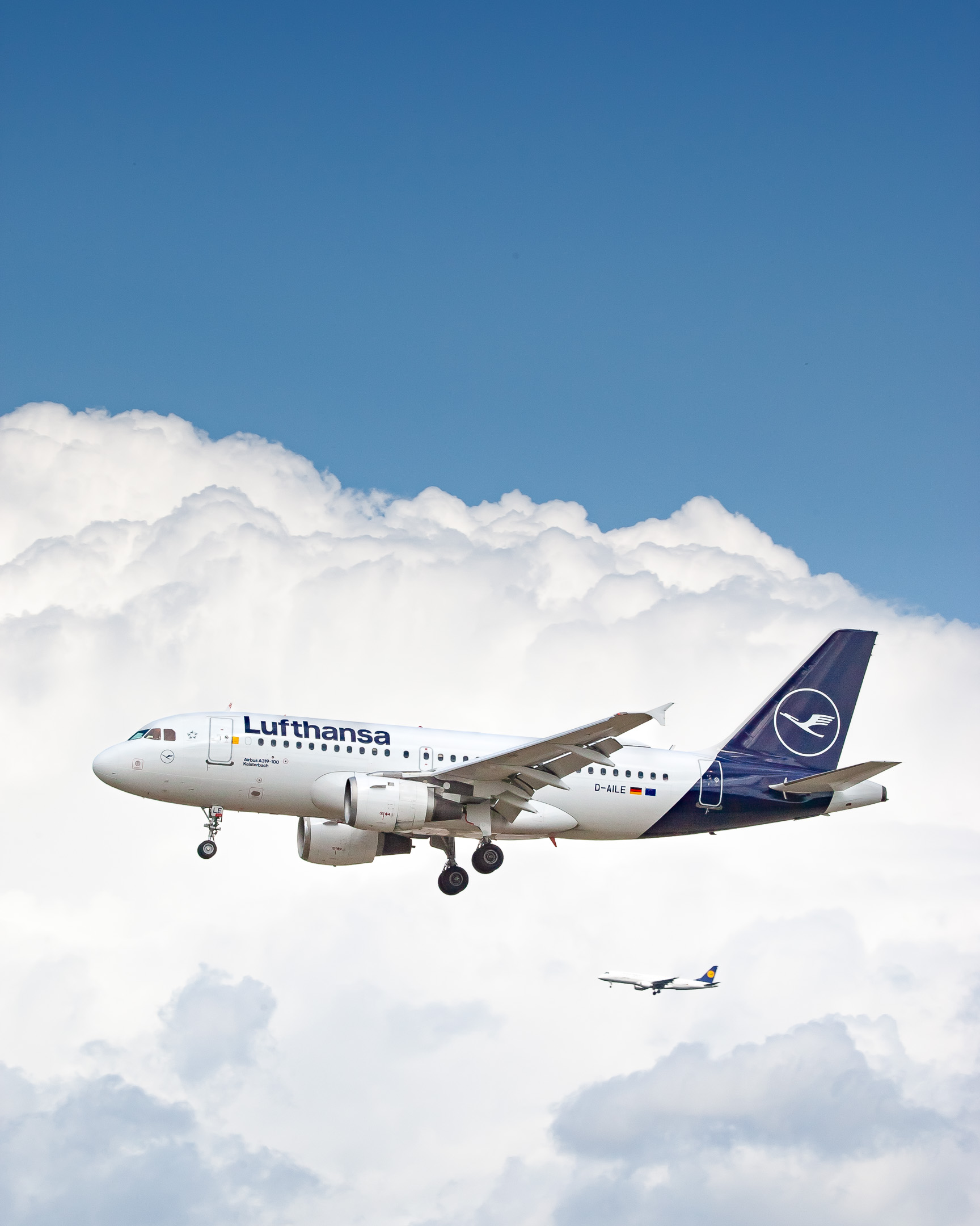 Lufthansa Airbus A319-100 "D-AILE" coming in on runway 07 center at Frankfurt Airport while another Lufthansa regional jet in the background approaches runway 07 right on a cloudy summer afternoon, August 2021.