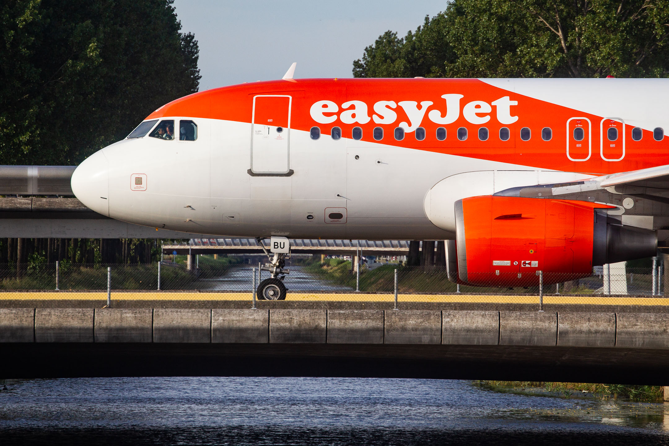 Easyjet Airbus A319-100 "G-EZBU" crossing a canal while taxiing to the Polderbaan runway at Amsterdam Schiphol Airport, July 2022