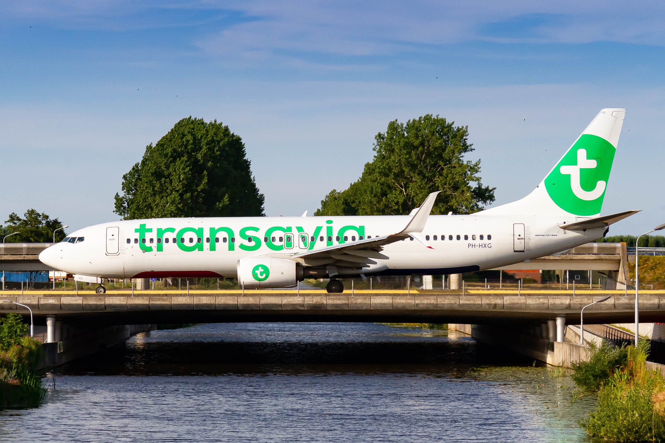 Transavia Boeing 737-800 "PH-HXG" taxxing over the bridge at Amsterdam Schiphol Airport on a warm summer evening, July 2022.