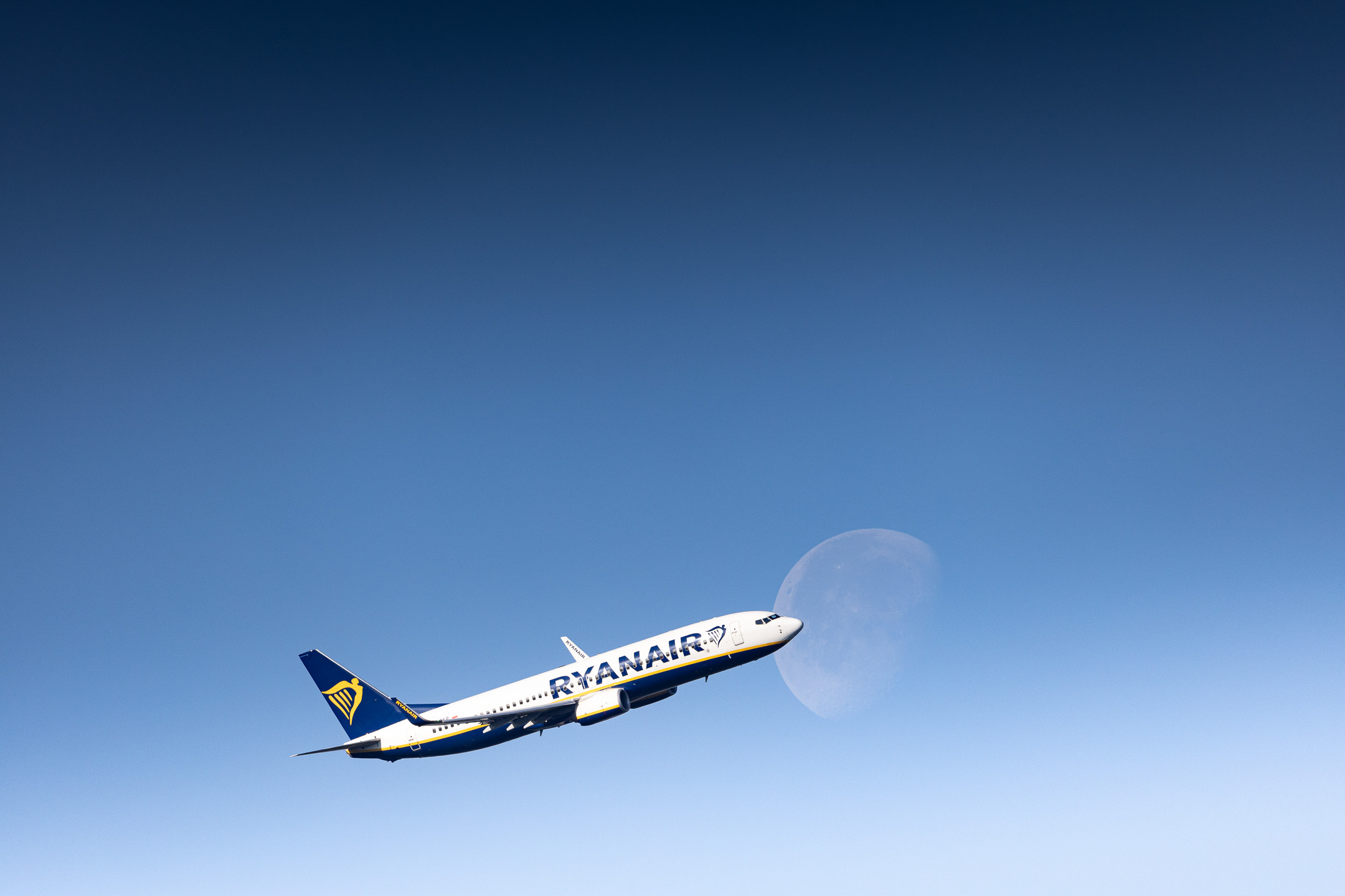 Ryanair Boeing 737-800 "SP-RKR" banking to the right in front of the moon after departure from runway 31R at Köln Bonn Airport on a bright and sunny morning, May 2024.